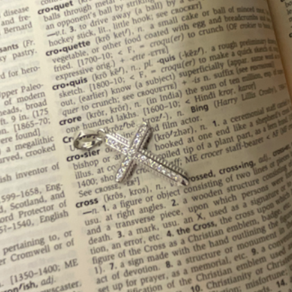 Silver cross pendant on an open book