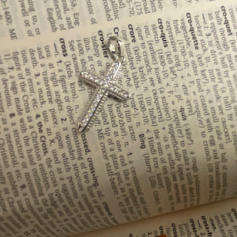 Silver cross pendant on an open book