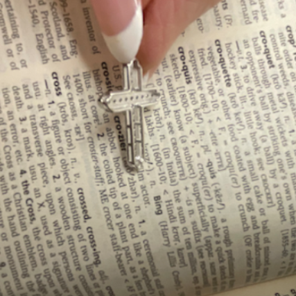 Hand holding a cross pendant over an open book
