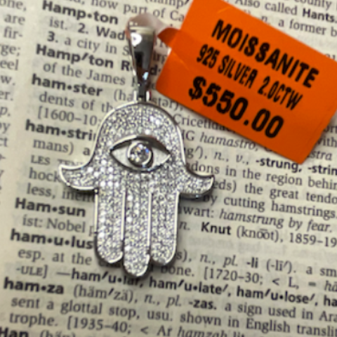 Silver Hamsa hand pendant with an orange Moissanite tag on a printed paper background