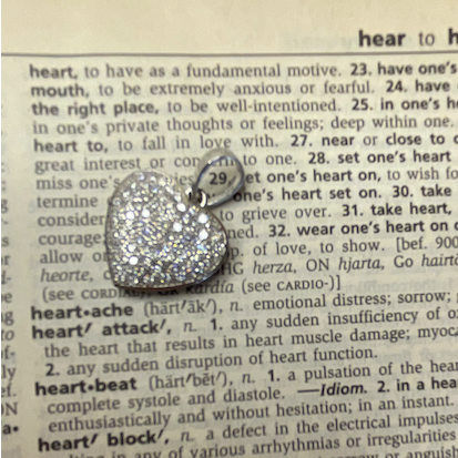 Heart-shaped silver pendant on a dictionary page