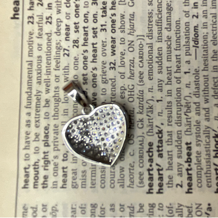 Heart-shaped silver pendant on a dictionary page
