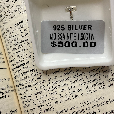 Silver brooch with '925 Silver' marking on a printed text background