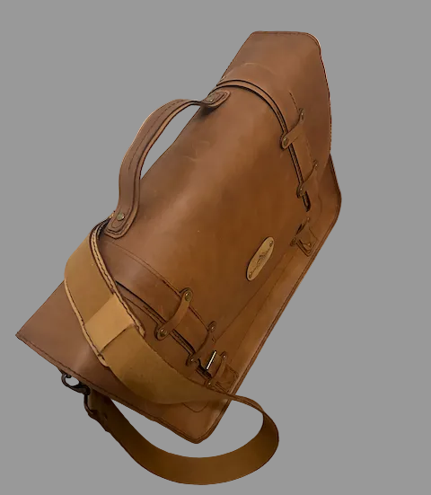 Brown leather briefcase on a wooden floor with a white wall background